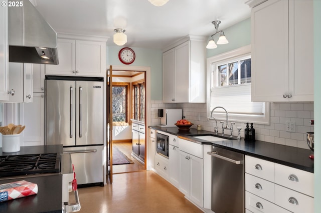 kitchen with dark countertops, backsplash, appliances with stainless steel finishes, a sink, and extractor fan