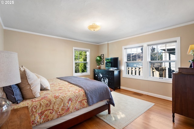 bedroom featuring ornamental molding, visible vents, baseboards, and wood finished floors