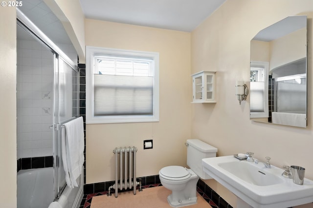 full bathroom featuring toilet, radiator heating unit, enclosed tub / shower combo, a sink, and tile patterned flooring