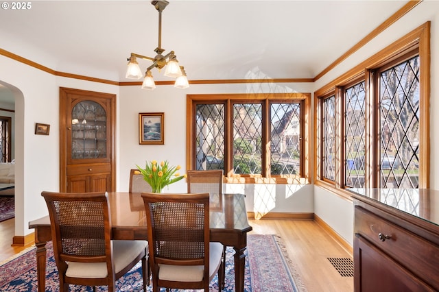 7115 N Chase Ave, Portland, OR 97217 - dining area with arched walkways, light wood-style flooring, and crown molding