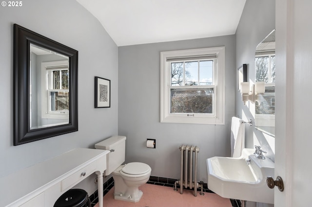 half bath featuring tile patterned flooring, toilet, a sink, baseboards, and radiator heating unit