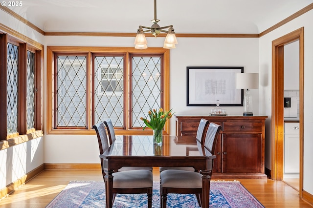 dining area with crown molding, light wood-style flooring, and baseboards