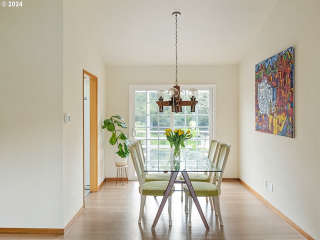 dining room with light wood-style floors, a chandelier, vaulted ceiling, and baseboards