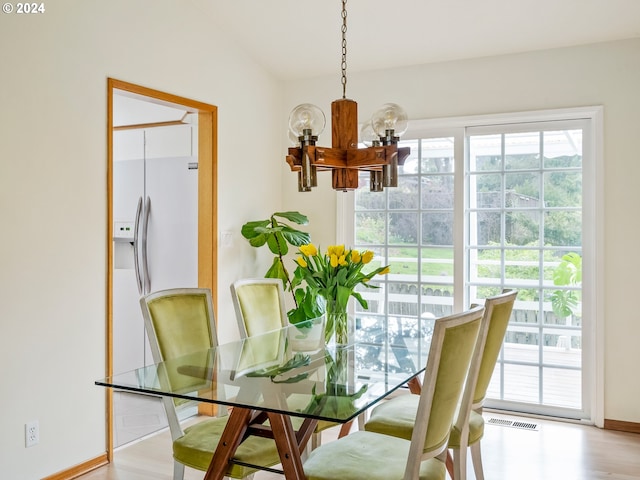 dining area with visible vents, light wood-style flooring, baseboards, and an inviting chandelier