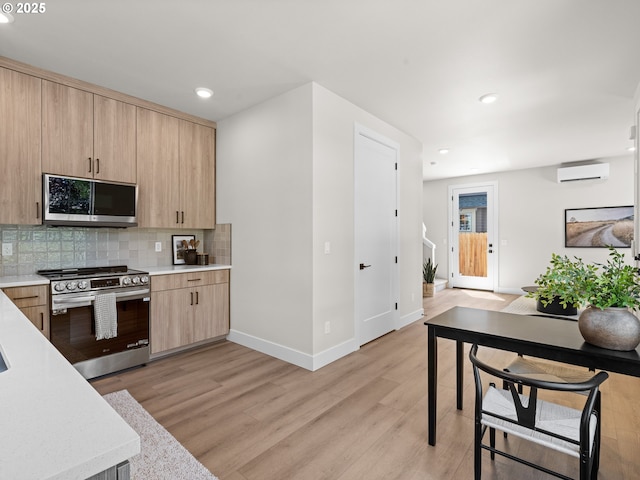 1562 NE 52nd Ave, Portland, OR 97213 - kitchen with stainless steel appliances, light brown cabinetry, an AC wall unit, baseboards, and light wood-type flooring