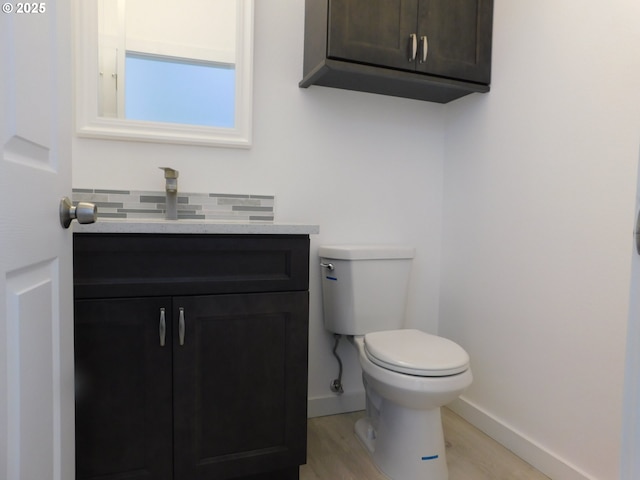 bathroom with hardwood / wood-style flooring, vanity, toilet, and decorative backsplash