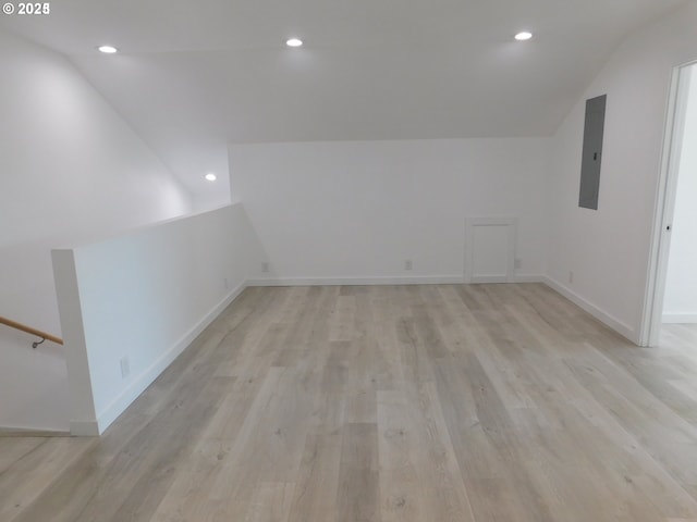 additional living space featuring electric panel, vaulted ceiling, and light hardwood / wood-style flooring