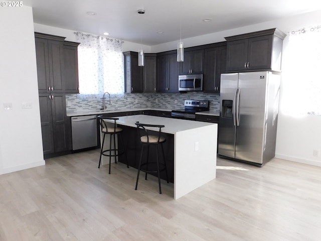 kitchen featuring a breakfast bar area, a center island, pendant lighting, stainless steel appliances, and backsplash