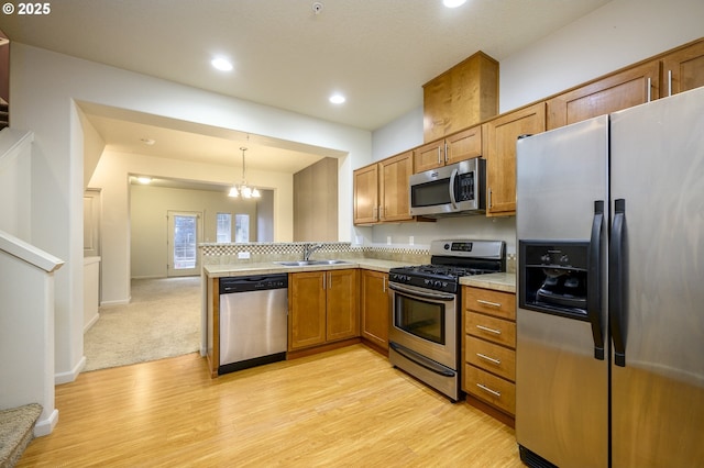 kitchen with sink, an inviting chandelier, decorative light fixtures, light carpet, and appliances with stainless steel finishes