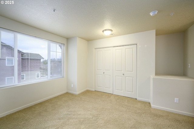 unfurnished bedroom featuring light carpet, a closet, and a textured ceiling