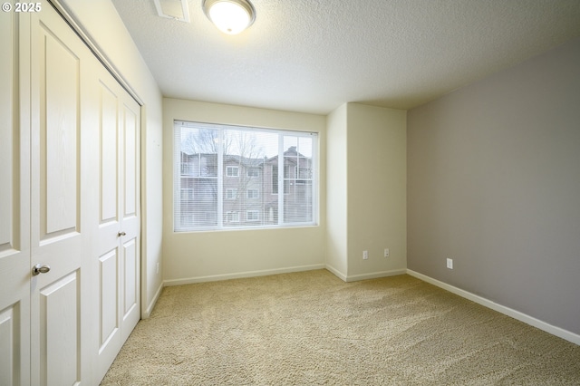 unfurnished bedroom with a textured ceiling and light carpet