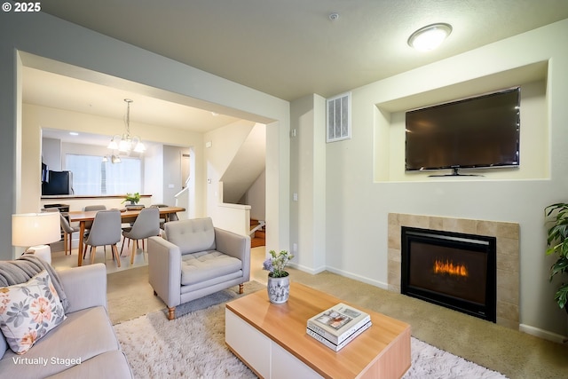 living room with light colored carpet, a fireplace, and an inviting chandelier