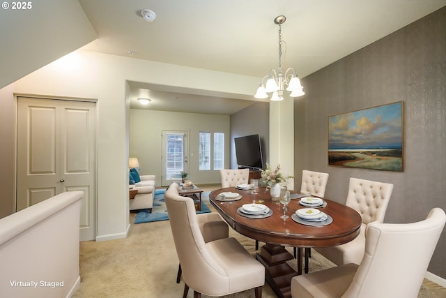 dining space featuring light carpet and an inviting chandelier