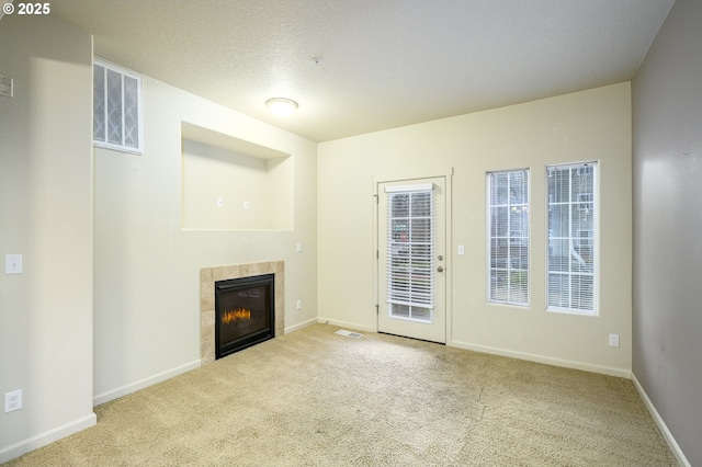 unfurnished living room with a fireplace, light colored carpet, and a textured ceiling