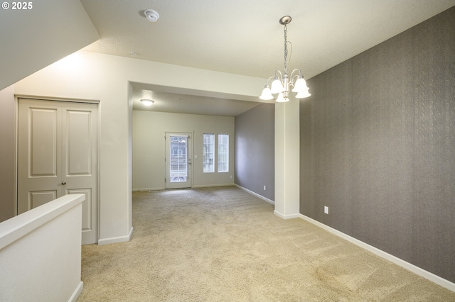 spare room with a notable chandelier and light carpet