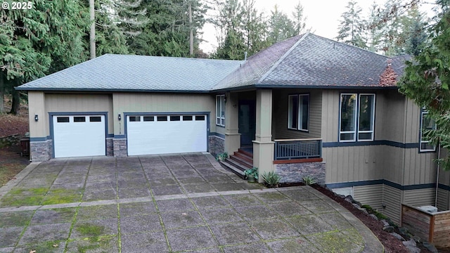 view of front facade with a garage, concrete driveway, roof with shingles, and stone siding