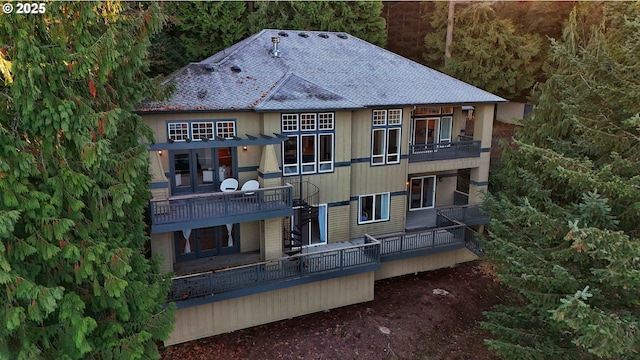 back of house featuring a shingled roof and a balcony