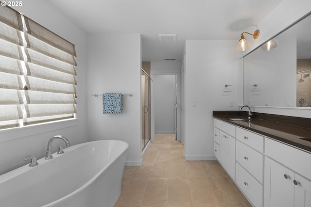 bathroom featuring tile patterned floors, a freestanding tub, a stall shower, baseboards, and vanity