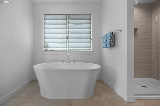 full bath featuring baseboards, a freestanding bath, a shower stall, and tile patterned flooring