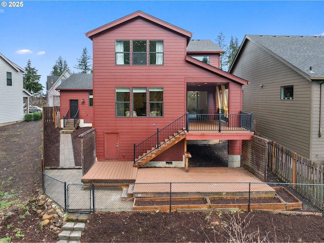 rear view of house featuring a fenced backyard, a deck, a vegetable garden, stairway, and a shingled roof