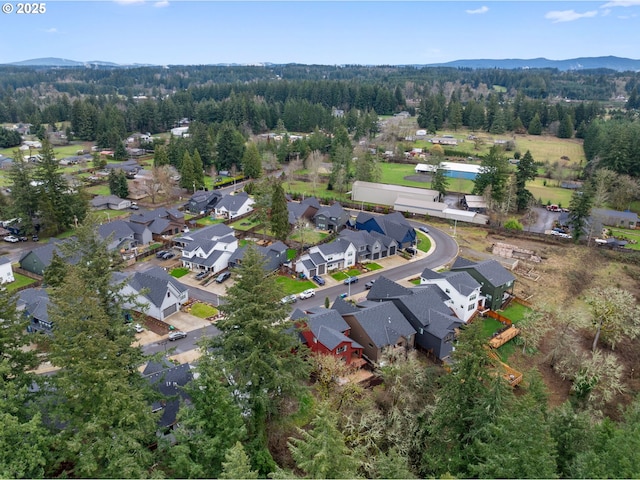 view of property location featuring nearby suburban area, a mountainous background, and a forest