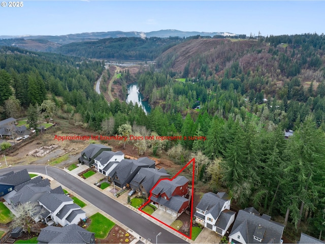 aerial view of residential area with a mountain backdrop, property parcel outlined, and a forest
