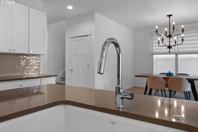 kitchen featuring dark countertops, decorative backsplash, recessed lighting, white cabinets, and a chandelier