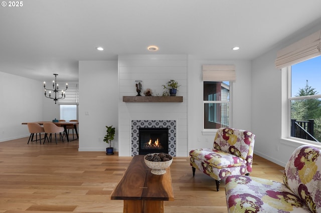 living area featuring a tiled fireplace, recessed lighting, light wood-type flooring, and a chandelier