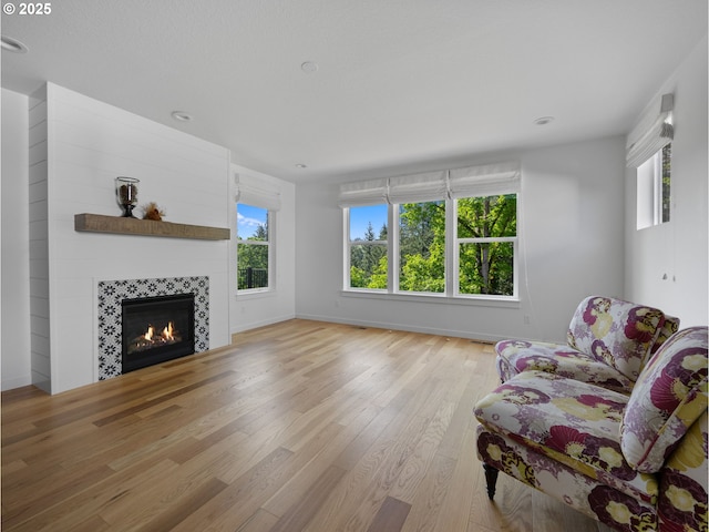 living area featuring wood finished floors, a fireplace, healthy amount of natural light, baseboards, and recessed lighting