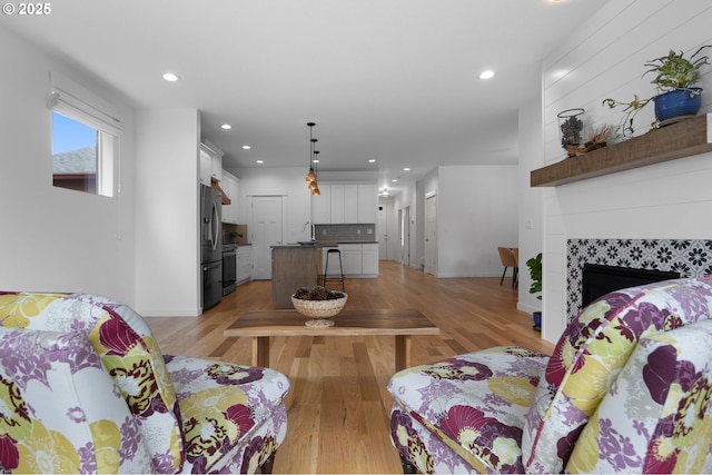 living room with light wood-style flooring, recessed lighting, baseboards, and a fireplace