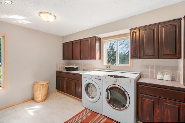 washroom featuring baseboards, washing machine and clothes dryer, cabinet space, a sink, and a textured ceiling