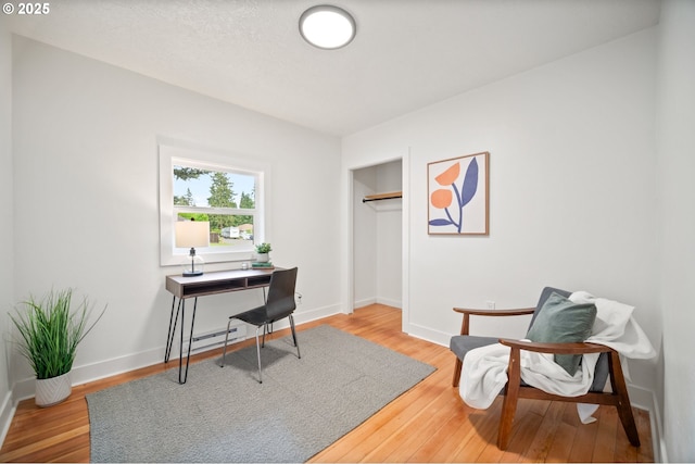 office space with wood finished floors, baseboards, and baseboard heating