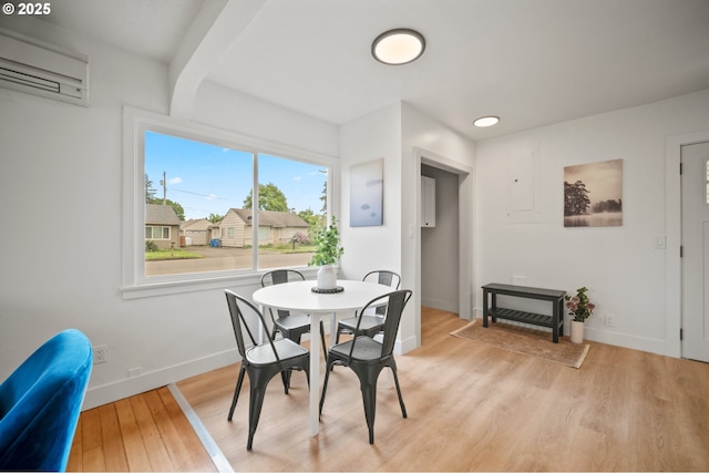 dining space with an AC wall unit, light wood-style floors, baseboards, and beamed ceiling