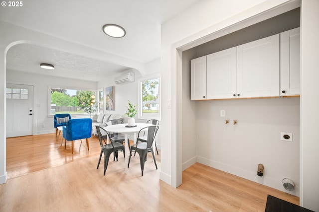 dining space featuring baseboards, light wood-style floors, and an AC wall unit
