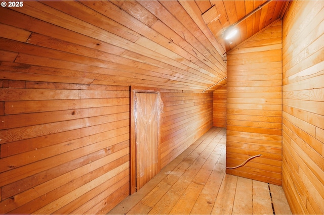 interior space featuring wooden walls, a sauna, vaulted ceiling, wooden ceiling, and light wood-style floors