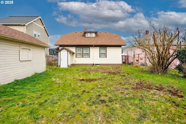 rear view of property featuring a lawn and fence