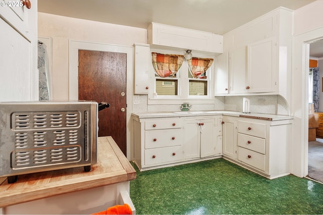 kitchen featuring a sink, white cabinets, dark floors, and light countertops