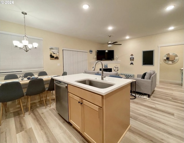 kitchen featuring sink, a center island with sink, light brown cabinets, dishwasher, and pendant lighting