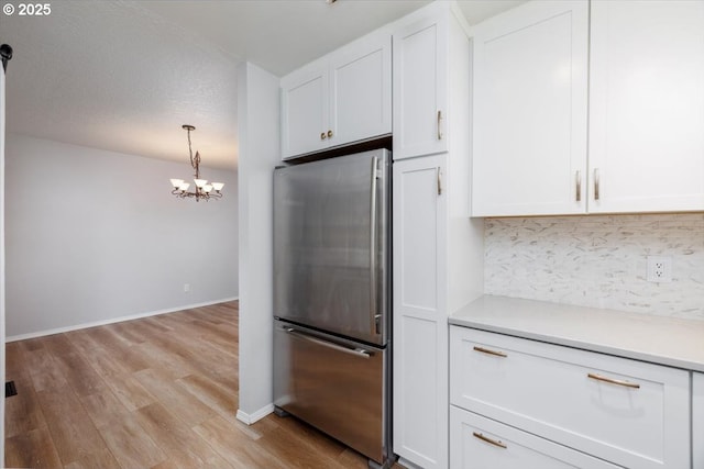 kitchen featuring white cabinets, stainless steel refrigerator, and a chandelier