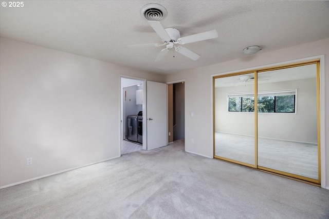 unfurnished bedroom featuring ceiling fan, light colored carpet, independent washer and dryer, and a closet