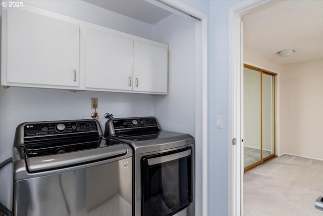 clothes washing area featuring cabinets, light carpet, and washing machine and clothes dryer