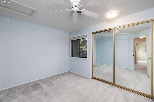 unfurnished bedroom with a textured ceiling, a closet, ceiling fan, and light colored carpet