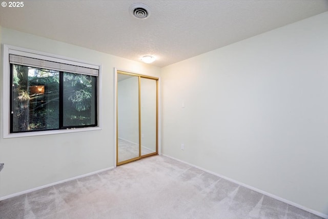 unfurnished bedroom featuring a closet, light colored carpet, and a textured ceiling