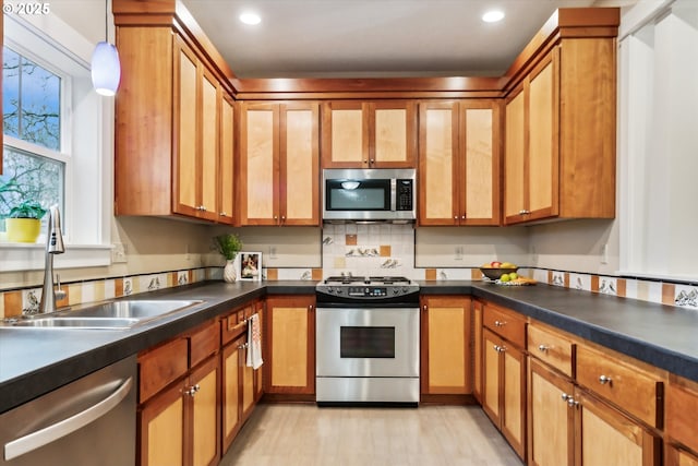 kitchen featuring dark countertops, brown cabinets, appliances with stainless steel finishes, and a sink