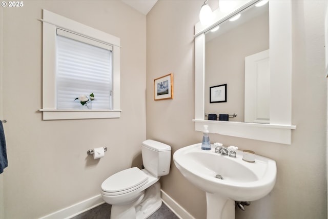 bathroom with toilet, baseboards, and a sink