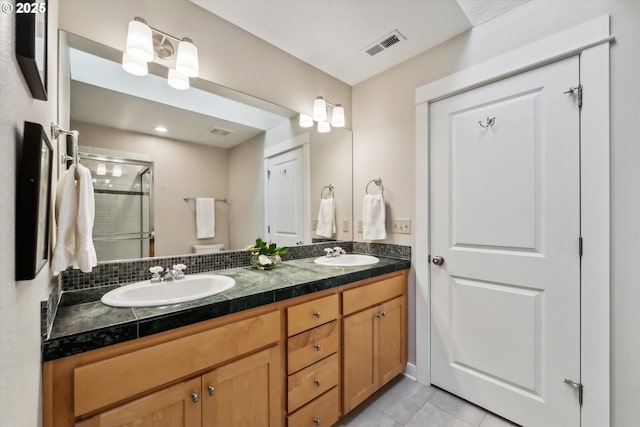 bathroom with a shower stall, double vanity, visible vents, and a sink