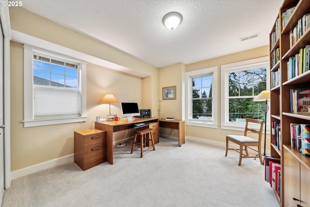 carpeted office space featuring baseboards, visible vents, and a textured ceiling