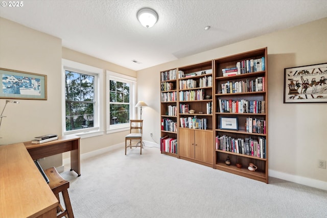 carpeted office with visible vents, baseboards, and a textured ceiling