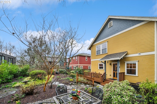 back of property featuring a deck and fence