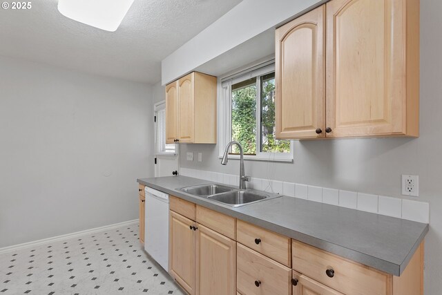 kitchen with white dishwasher, sink, a textured ceiling, and light brown cabinets